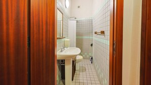 Une salle de bain avec une porte en bois, un lavabo, des toilettes et un espace douche.