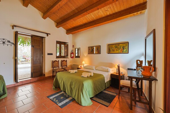 A room with a bed, a table, a chair, a door, and a window.