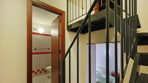 Una escalera con barandillas de metal que lleva a una habitación con una cama y una pequeña mesa.