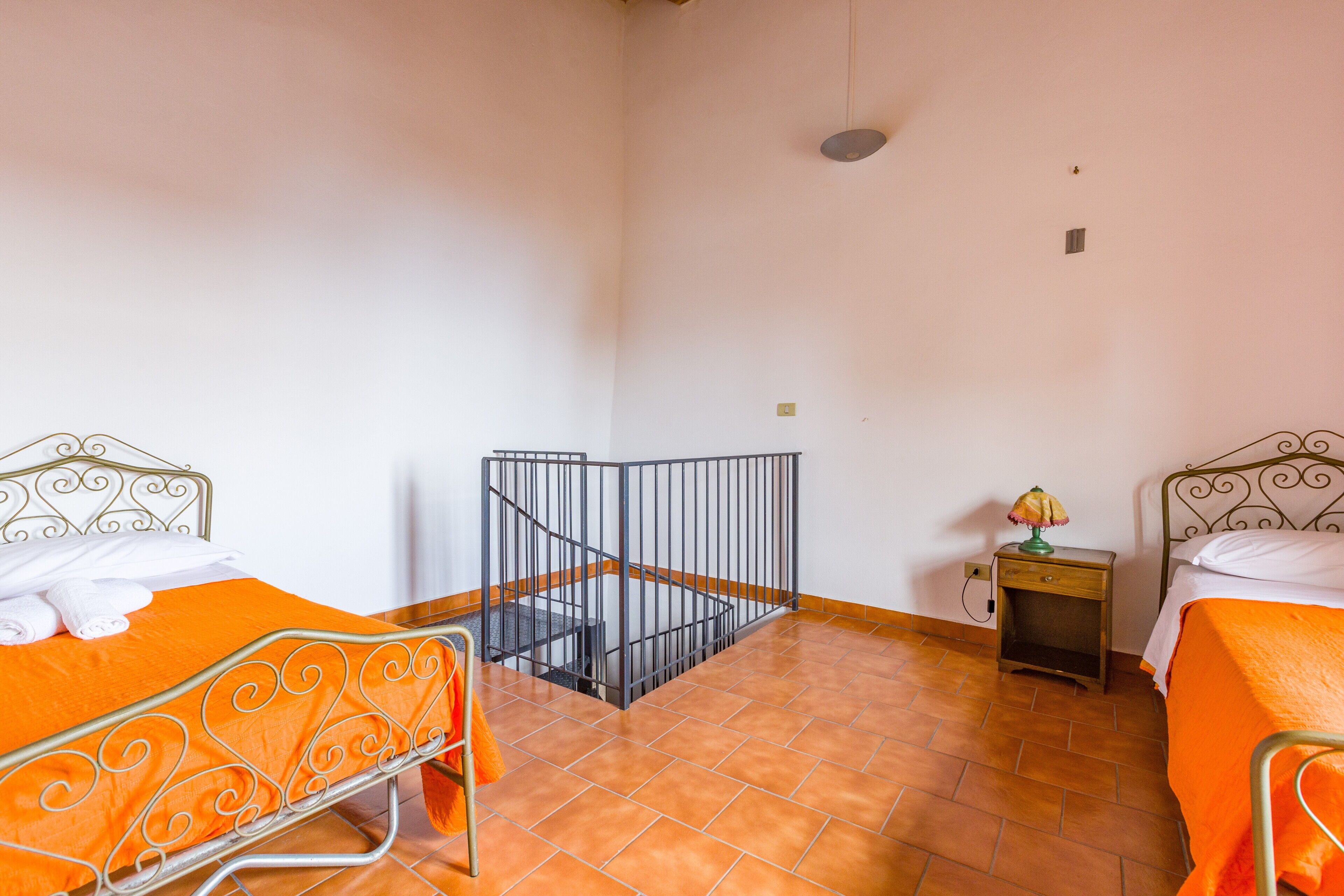 Une chambre avec deux lits, une petite table, une table de chevet et un escalier.