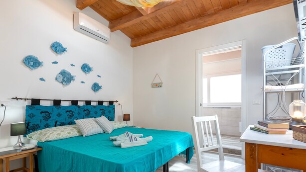 Un dormitorio con cama, mesitas de noche, escritorio, silla y ventana.