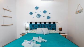A bedroom with a bed, pillows, a bedside table, a lamp, and wall decorations.