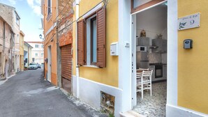 Una calle estrecha flanqueada por edificios, con una puerta a la vista y un letrero que indica el número.