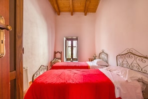 Une chambre avec deux lits, une porte en bois, une fenêtre et une table de chevet.