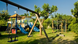 Ein Spielplatz mit Schaukeln, einer Rutsche und einer Kletterkonstruktion.