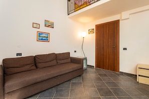 A living room with a brown sofa, a wooden door, and a ceiling light. - Room 'Cosimo' with Mountain View, Wi-Fi and Air Conditioning (Taormina)