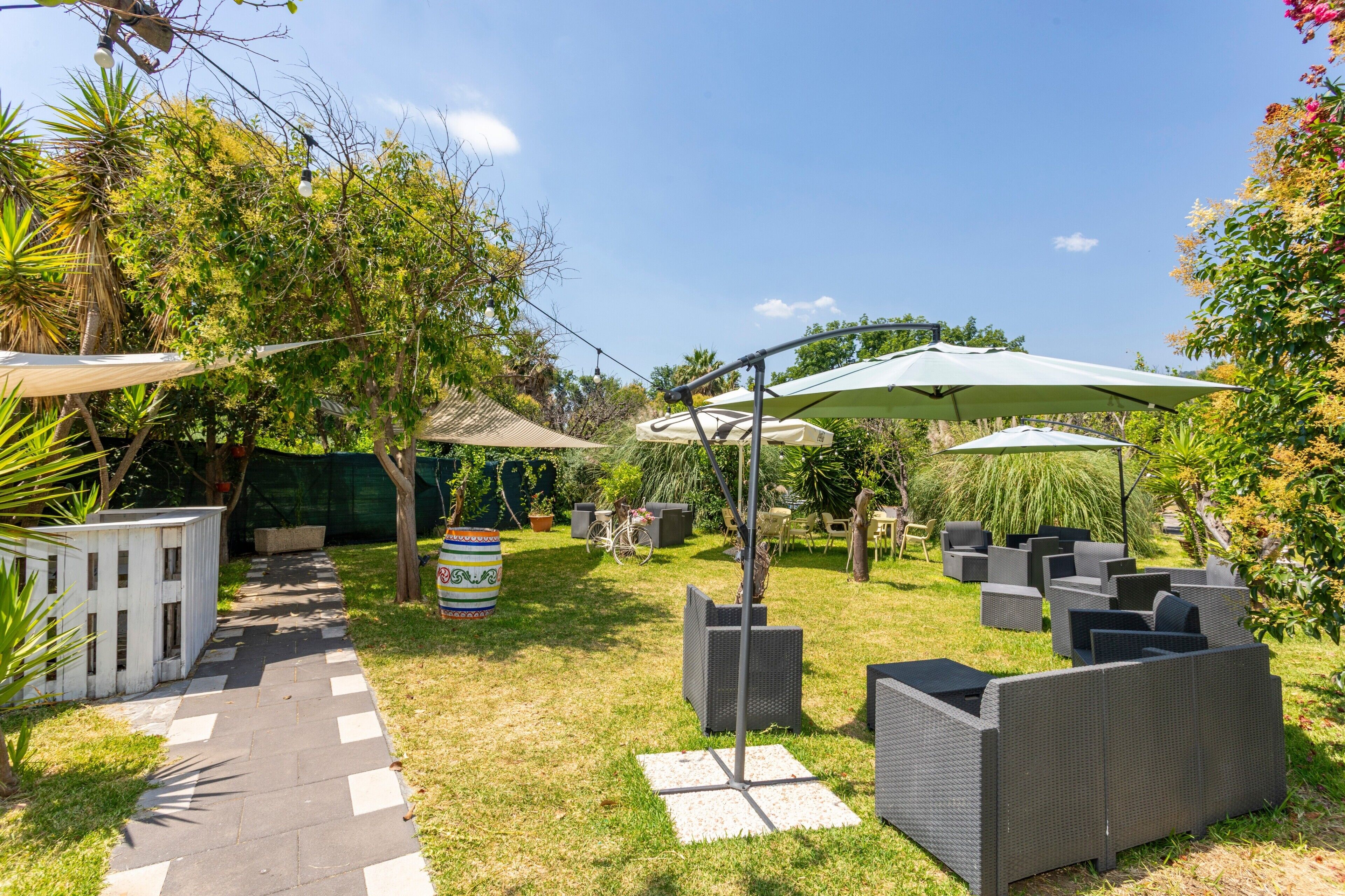 Un patio con mobiliario exterior, sombrillas y un sendero.