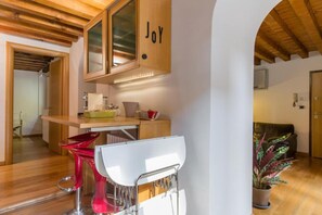 A kitchen with wooden cabinets, a countertop, and a red chair.