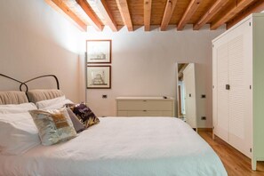 A bedroom with a wooden ceiling, a bed with multiple pillows, a dresser, and a closet.