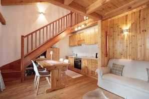 A wooden interior with a staircase, kitchen, dining area, and a sofa.