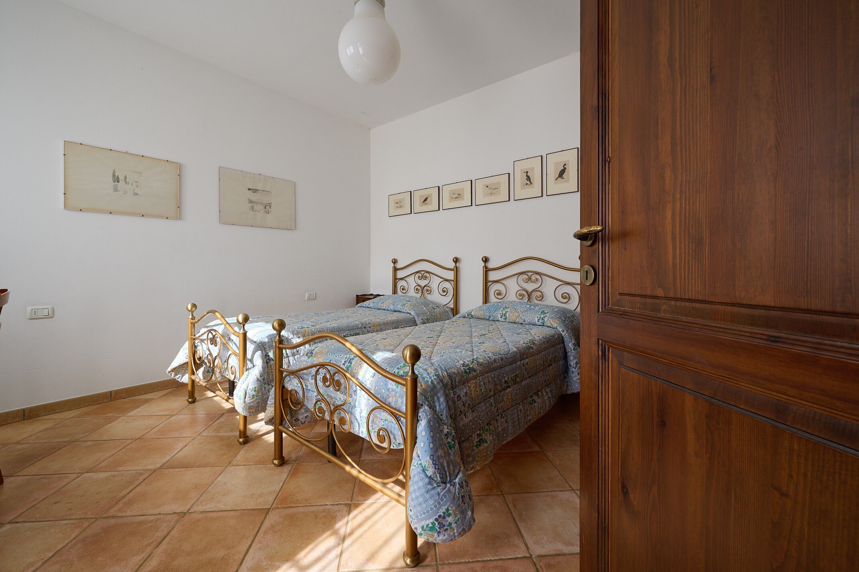 A bedroom with two beds, a wooden wardrobe, and wall-mounted pictures.