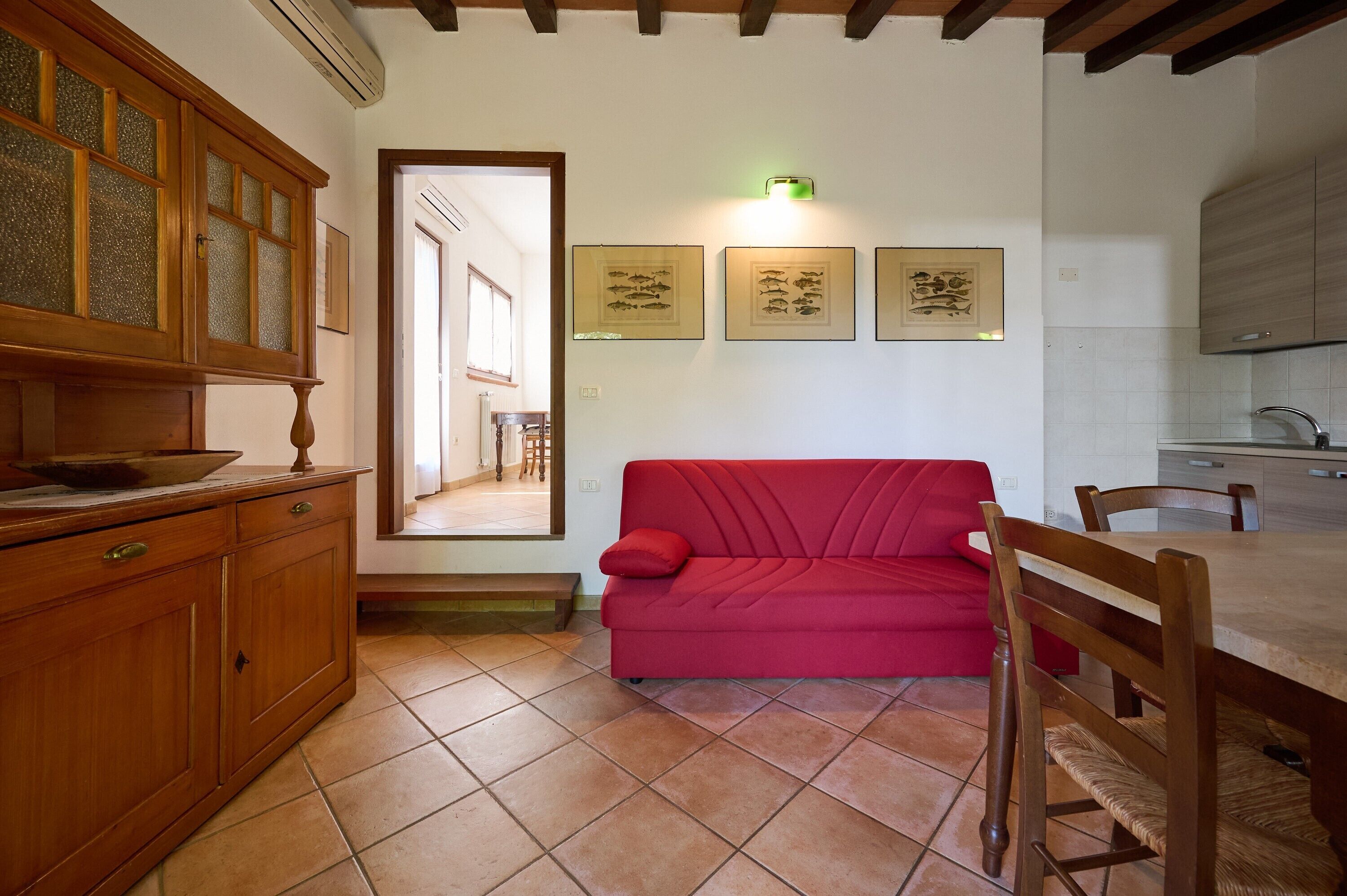 Una cocina con armarios de madera, un sofá rojo y una mesa de comedor.