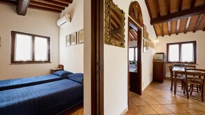 Une pièce comprenant deux lits, une table à manger avec des chaises, un coin cuisine et un grand miroir décoratif.