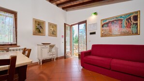 A dining area with a table and chairs, a red sofa, and a painting on the wall. - Holiday Home 'La Carraia' with Private Terrace, Wi-Fi and Air Conditioning (Suvereto)