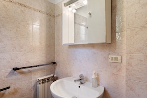 Un baño con lavamanos blanco, espejo con luces, toallero y retrete.