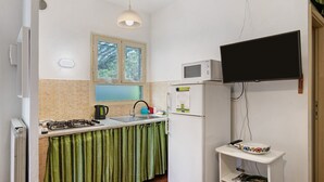 A compact kitchen with a gas stove, sink, microwave, and a small refrigerator. - Holiday Home 'Chiara' with Private Terrace, Wi-Fi and Air Conditioning (Marina di Pietrasanta)