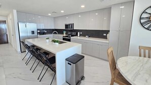 Una cocina moderna con una isla central, electrodomésticos de acero inoxidable y encimera de mármol.