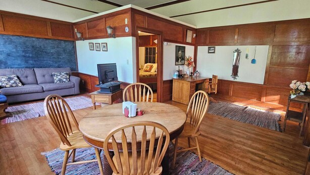 Un accogliente soggiorno con un tavolo da pranzo in legno, sedie, un divano e un televisore.