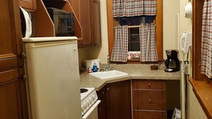 Una cucina compatta con frigorifero, microonde, fornello, lavandino e macchina per il caffè.