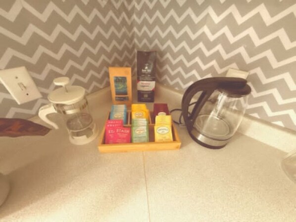 A kitchen area with a coffee maker, a kettle, and a tray of tea bags.