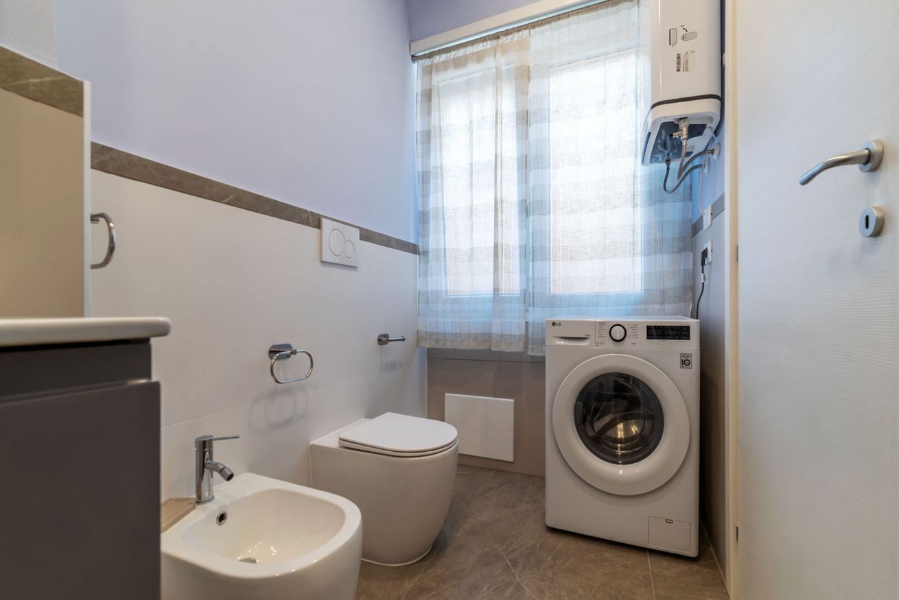 Une petite salle de bain comprenant des toilettes, un bidet et un lave-linge.