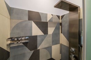 Bathroom features a geometric tile pattern and a stainless steel shower enclosure with a control panel.