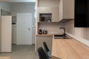 Kitchen area with microwave oven, kettle, and sink, integrated into a larger room.