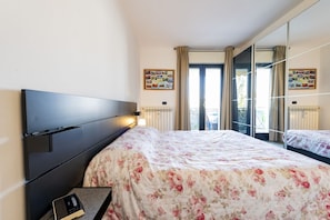 Une chambre à coucher avec un lit, une table de chevet, un miroir et une fenêtre avec des rideaux.
