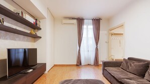 A modern living room with a flat-screen TV, a sofa, a coffee table, and a bookshelf. - GuestHost - Arco della Pace Apartment Milan (Milan)