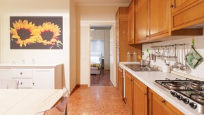 A kitchen with wooden cabinets, a stove, and a countertop with kitchen utensils. - GuestHost - Arco della Pace Apartment Milan (Milan)