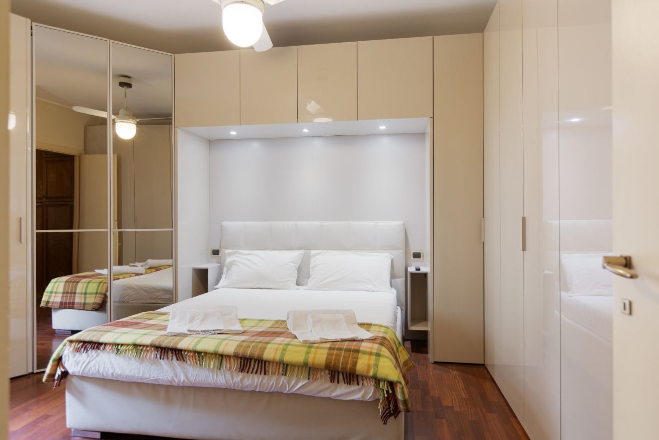 Ein Schlafzimmer mit einem Bett, Nachttischen, einem Spiegel und einem Kleiderschrank.