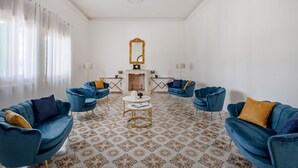 Une pièce avec quatre fauteuils bleus, une table basse blanche, un miroir et un sol à motifs.