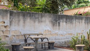 A patio with a table and stools, surrounded by a concrete wall and plants. - GuestHost - Cozy detached villa of 156 sqm, on two levels, able to accommodate up to 9 people. The property is located in Pizzolungo, a coastal hamlet of Erice, an oasis of peace overlooking the crystalline sea of ​​​​western Sicily. A few minute (Pizzolungo)