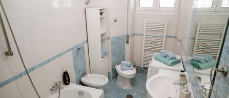 A bathroom with a bathtub, bidet, toilet, and sink.