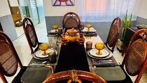 A dining area with a long table set for four, surrounded by wooden chairs with woven backs. - Tropical Mid-Century Modern B&B in Merida's Centro, Azul (Mérida)
