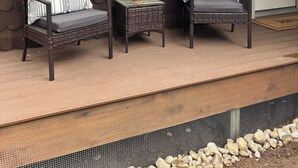 Une véranda avec deux fauteuils en osier, une petite table sur laquelle est posée une plante en pot et une grande fenêtre.