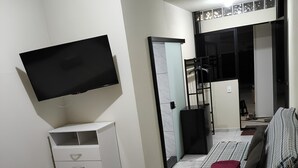 Ein Schlafzimmer mit Bett, Fernseher, Kleiderschrank und einer Tür, die auf einen Balkon führt.