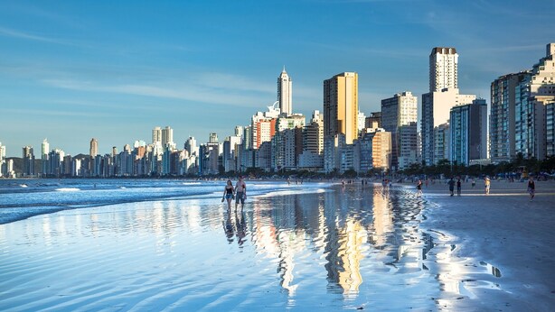 Ein Strand mit einer Stadtkulisse im Hintergrund.