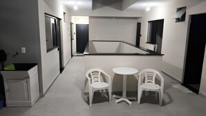Eine kompakte Küchenzeile mit einem kleinen Esstisch und zwei Stühlen, einem Kühlschrank und einer Mikrowelle.