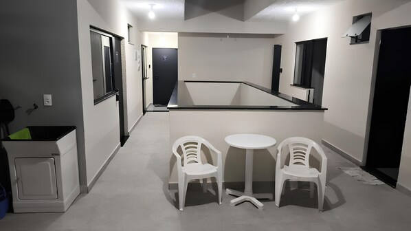 A compact kitchen area with a small dining table and two chairs, a refrigerator, and a microwave.