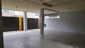 Ein leerer Innenraum mit Betonboden, einem schwarzen Metallgitter und einer gelben Säule.