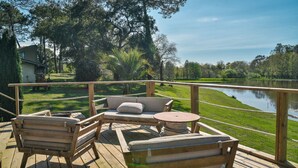 A wooden deck with outdoor furniture, a view of a lake, and surrounding greenery. - Les Nymphéas, Landes haven of peace, nature & private pond (Angresse)