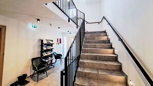 A staircase with a black railing leading to an upper floor. There is a bookshelf with magazines and a chair in the lower area. - Nice apartment for 5 people with WIFI, TV and balcony (Wildschönau)