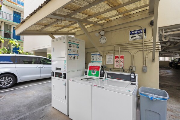 Une laverie équipée de machines à laver industrielles, avec une voiture garée devant.