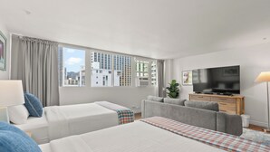 A modern hotel room with a large bed, a sofa, a TV, and a view of the cityscape. - Legal Studio with AC and WiFi, Just One Block from Waikiki Beach (Honolulu)