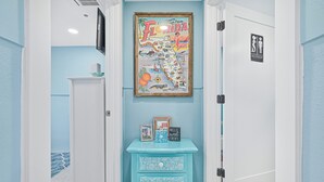 Een gang met een kaart van Florida, een klein blauw dressoir en een deur met een toiletbordje.