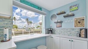 Een keuken met uitzicht op palmbomen, een bord waarop 'MYSTIC BEACH' staat en een wijnkaart aan de muur.