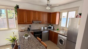 Una cocina moderna con armarios de madera, encimeras de granito, horno empotrado, microondas, lavavajillas y un refrigerador de acero inoxidable.