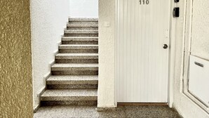 A white door with the number 110, a set of stone steps leading up to it, and a textured wall on the left.