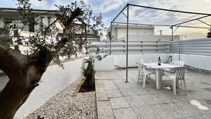 A patio area with a table and chairs, a pergola, and a tree.